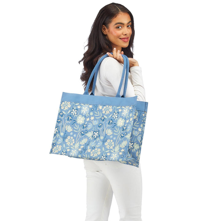 Woman holding a blue floral-patterned tote bag on a white background