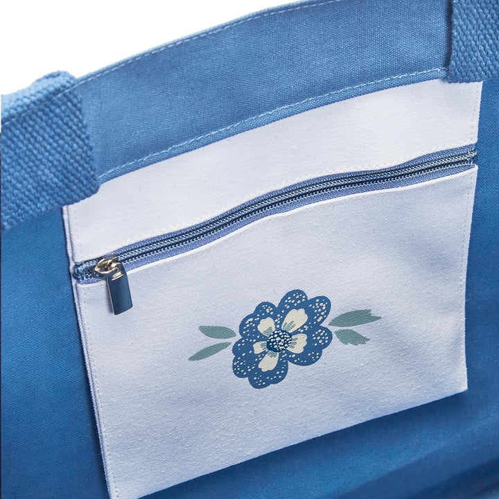 Blue bag with a white pocket featuring a floral design on a white background