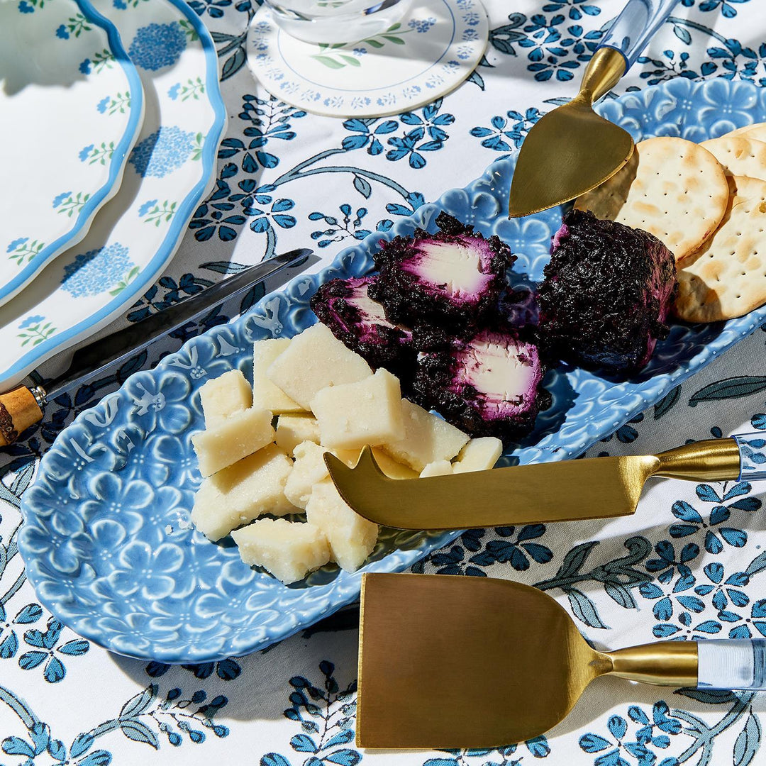 Blue patterned plate with cheese and crackers on a matching tablecloth.