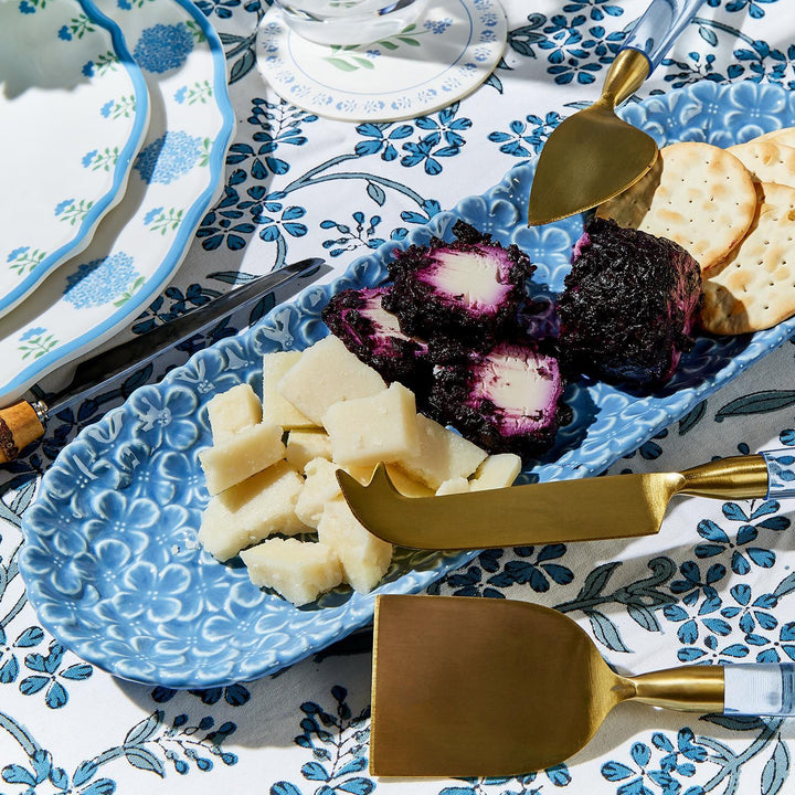 Blue patterned plate with cheese and crackers on a matching tablecloth.