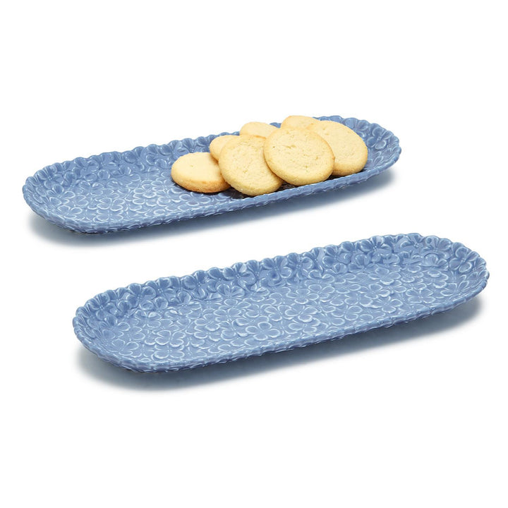 Two blue textured ceramic trays with cookies on a white background