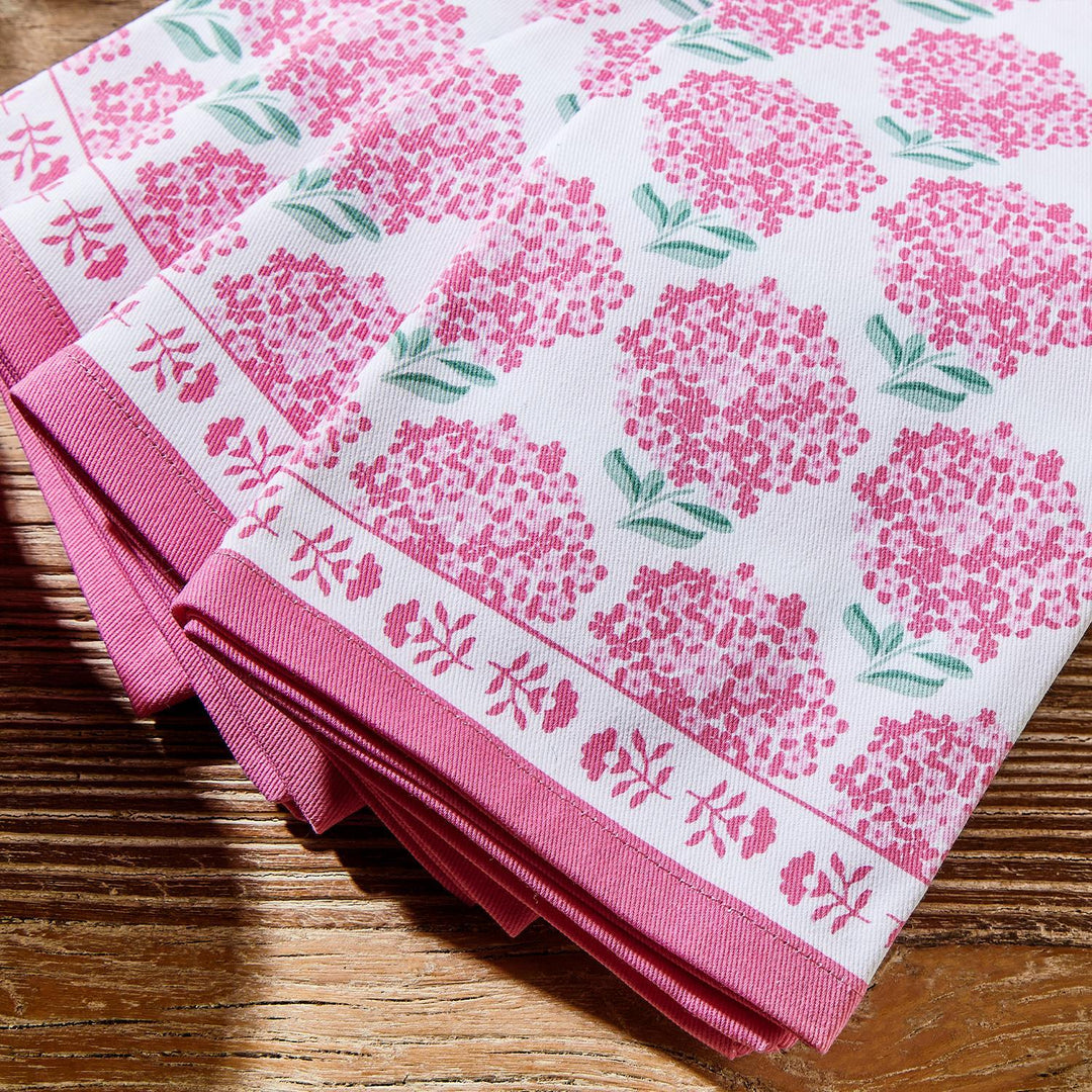 Stack of pink floral-patterned paper napkins on a wooden surface