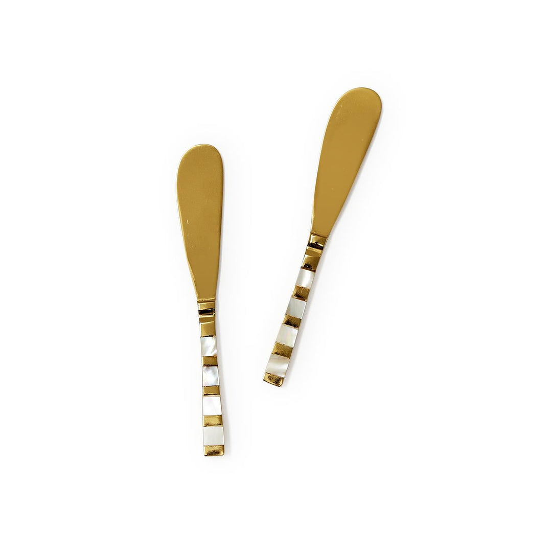 Two gold butter knives with black and white patterned handles on a white background