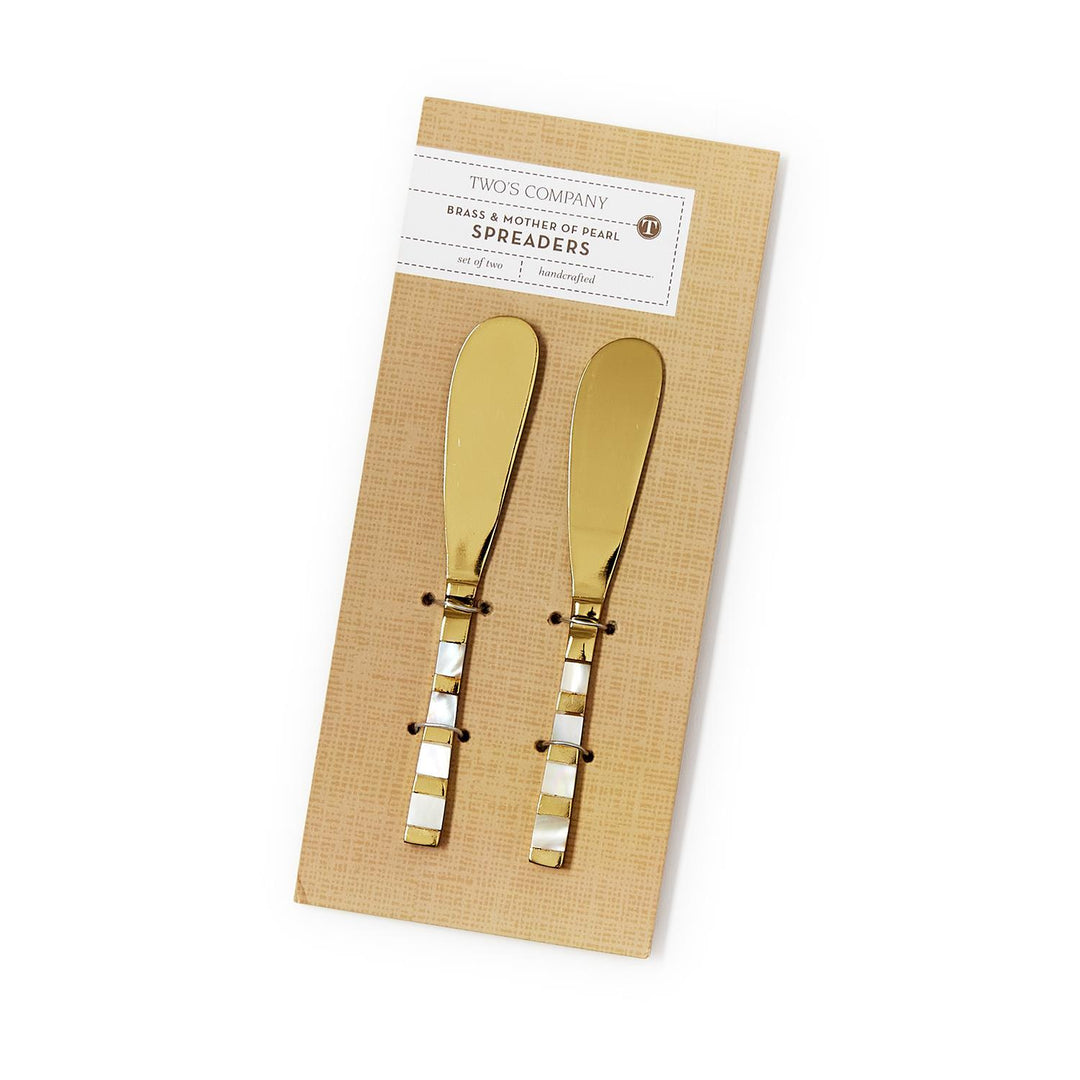 Two gold butter knives on a beige card with a brand label.