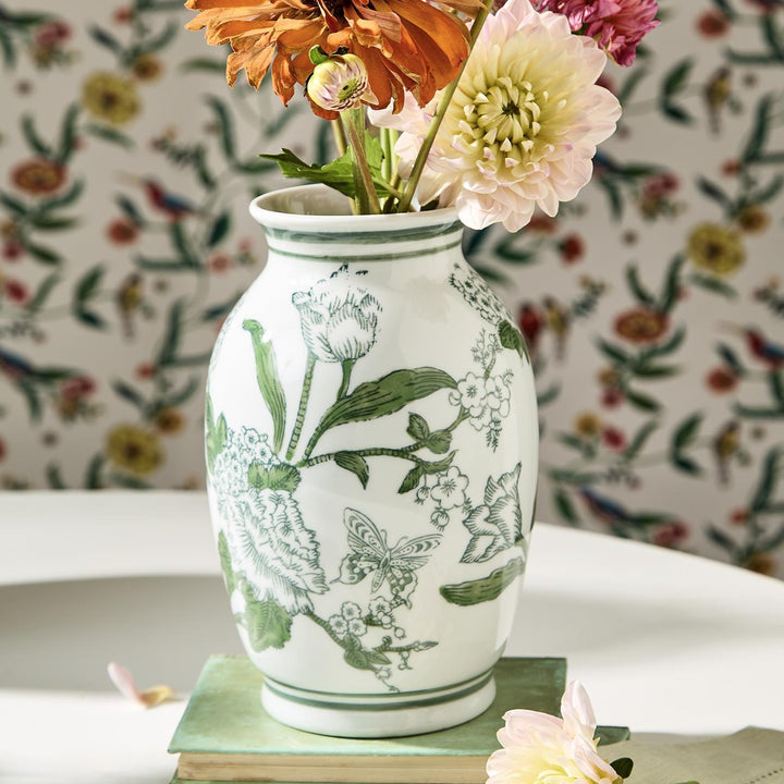 Decorative vase with floral patterns on a surface with a floral wallpaper background