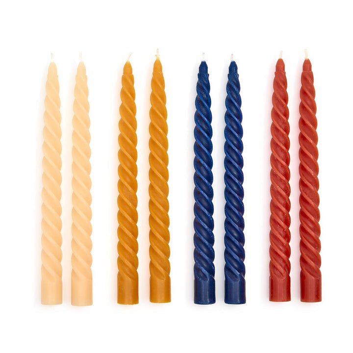 Set of twisted candles in beige, orange, blue, and red on a white background