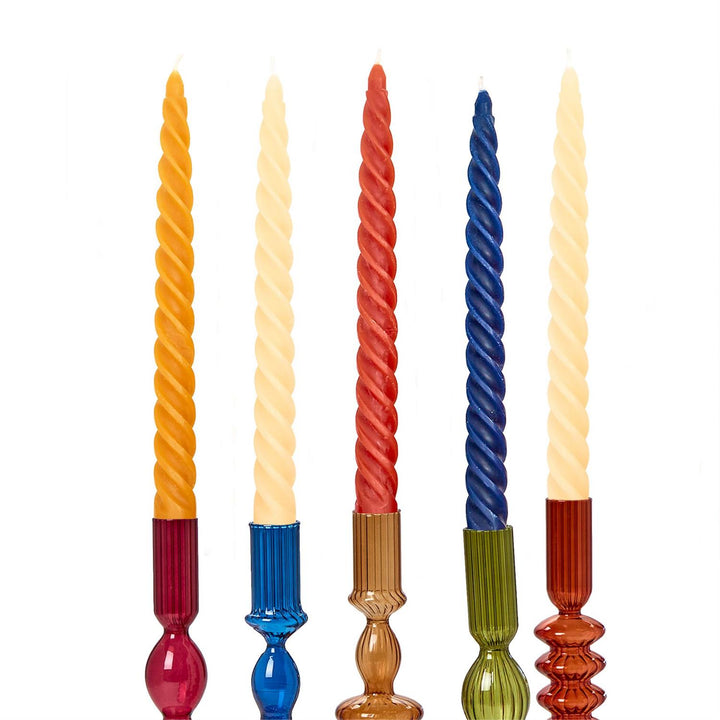 Set of five colorful twisted candles with decorative bases on a white background