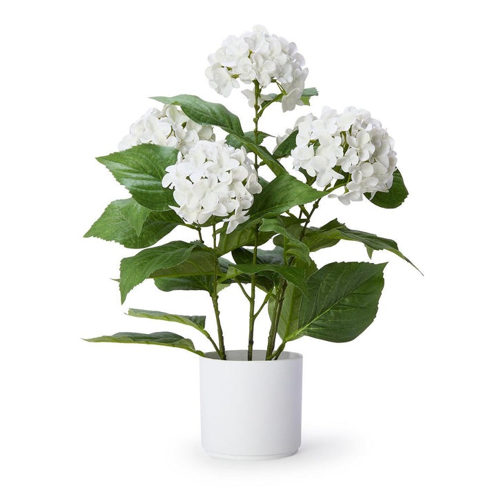 Artificial plant with white flowers and green leaves in a white pot on a white background