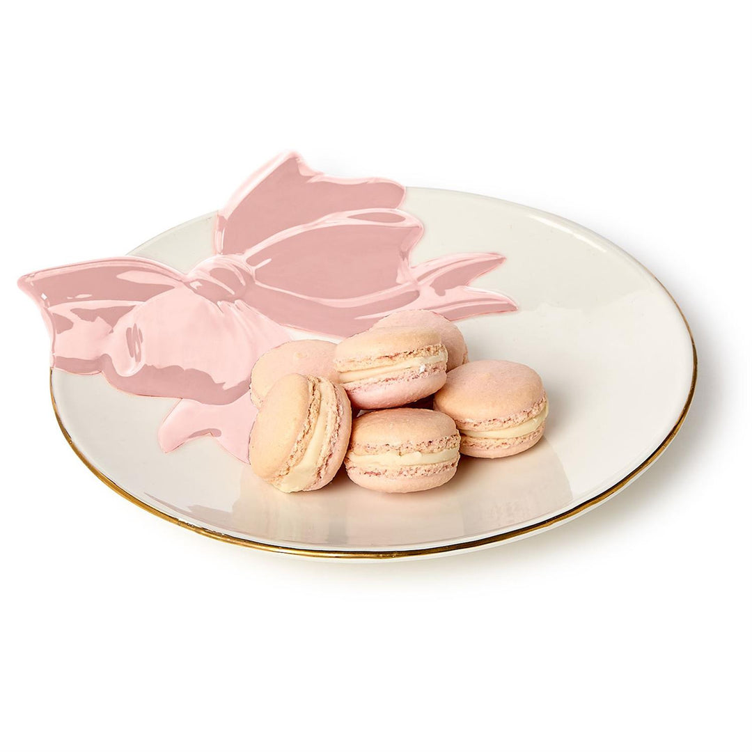 Pink macarons on a decorative plate with a pink bow design.