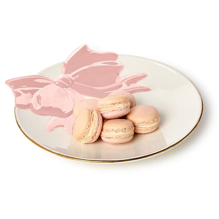 Pink macarons on a decorative plate with a pink bow design.