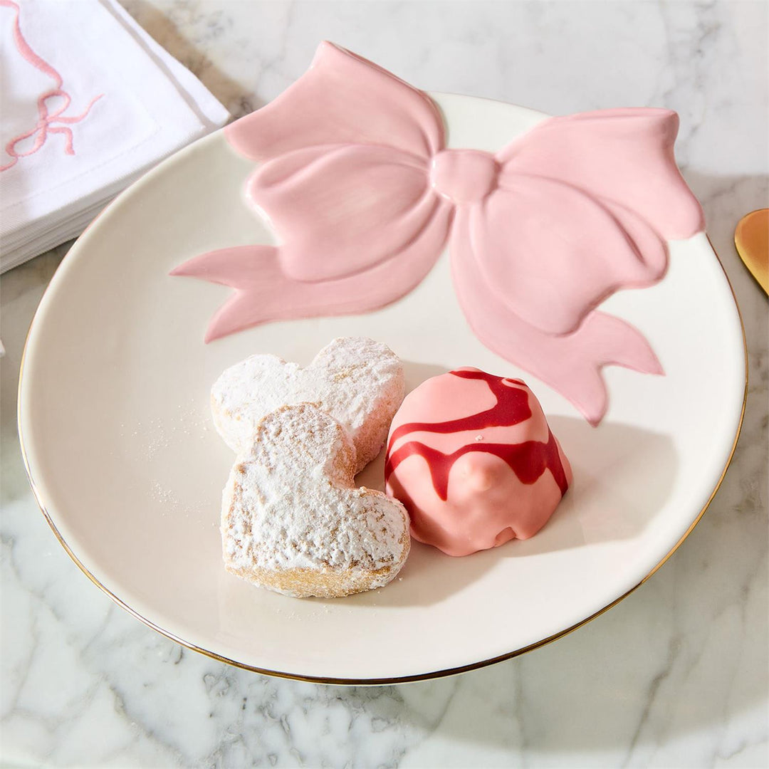 Decorative plate with pink bow and two cookies on a marble surface
