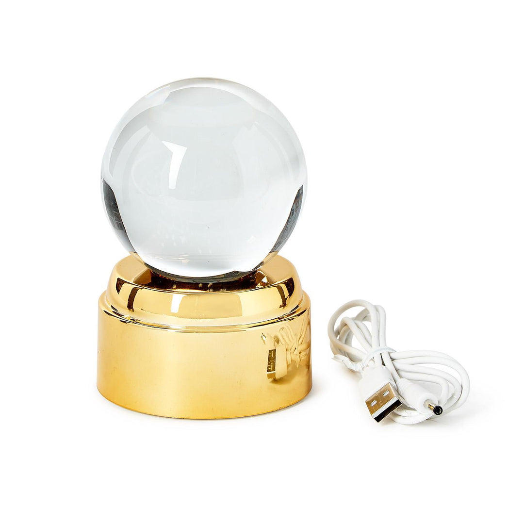 Clear glass sphere on a gold base with a USB cable on a white background