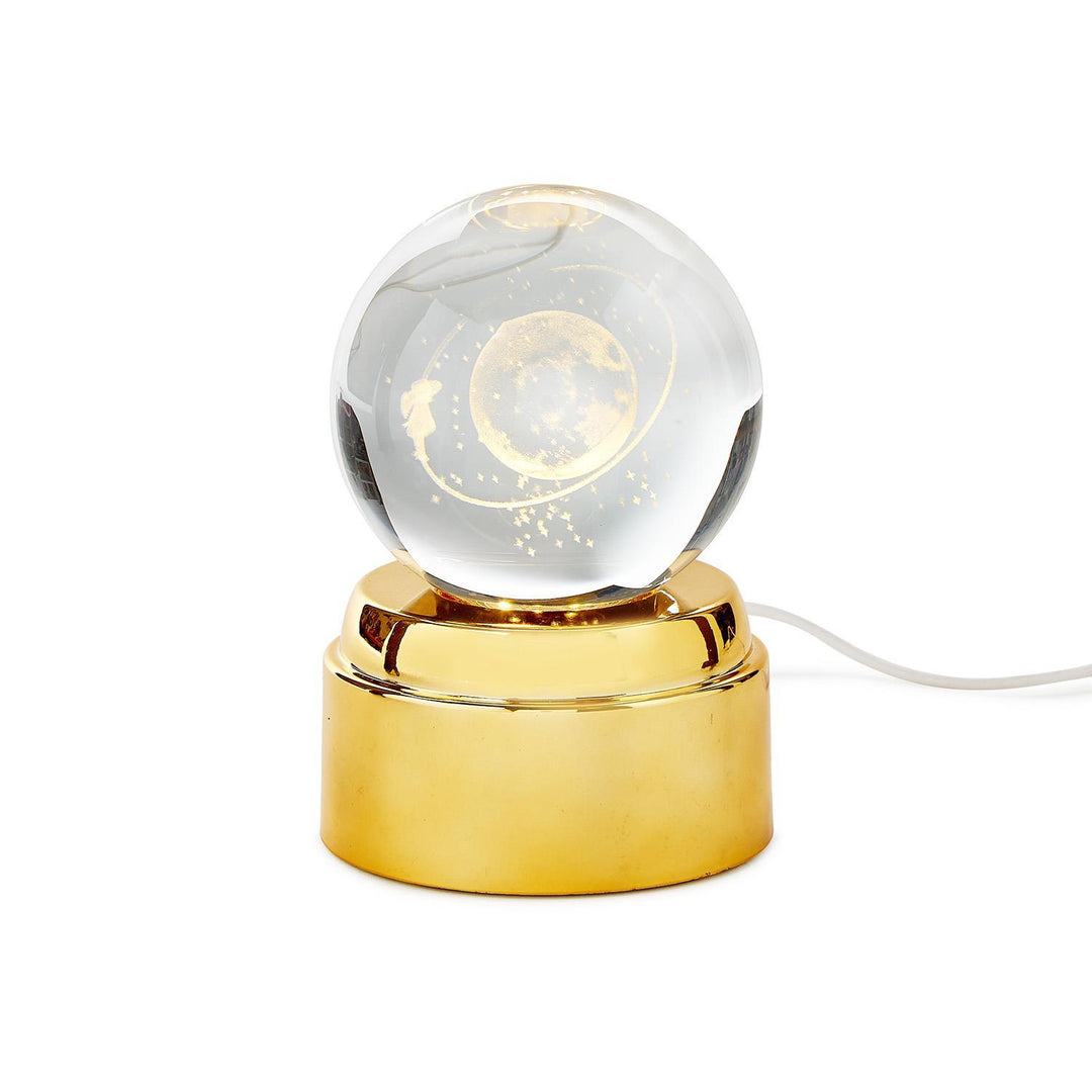 Decorative lamp with glass sphere and gold base on a white background