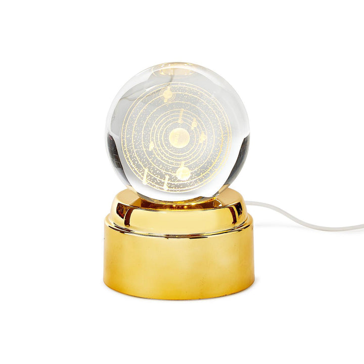 Decorative lamp with a clear glass sphere and gold base on a white background