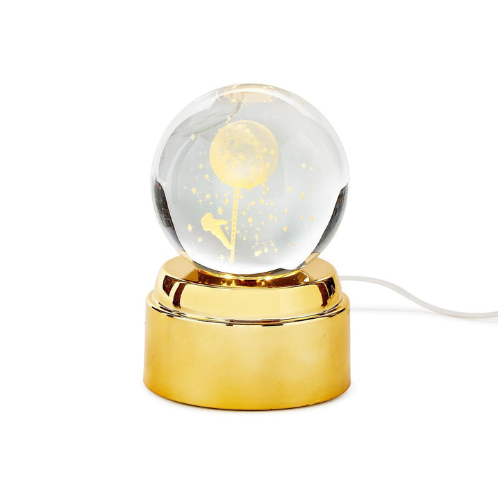 Decorative lamp with a gold base and clear glass sphere on a white background