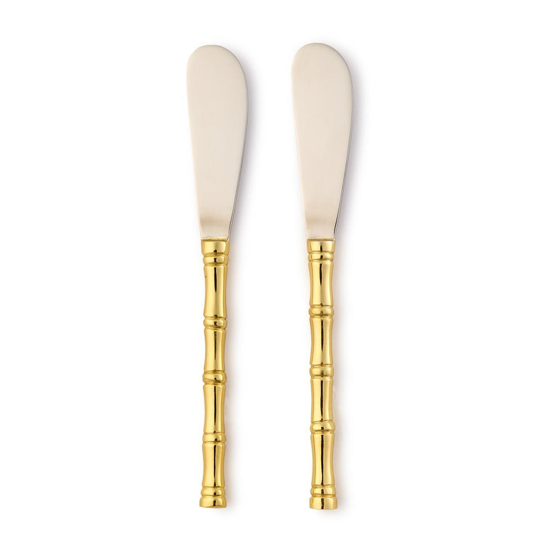 Two butter knives with gold handles on a white background