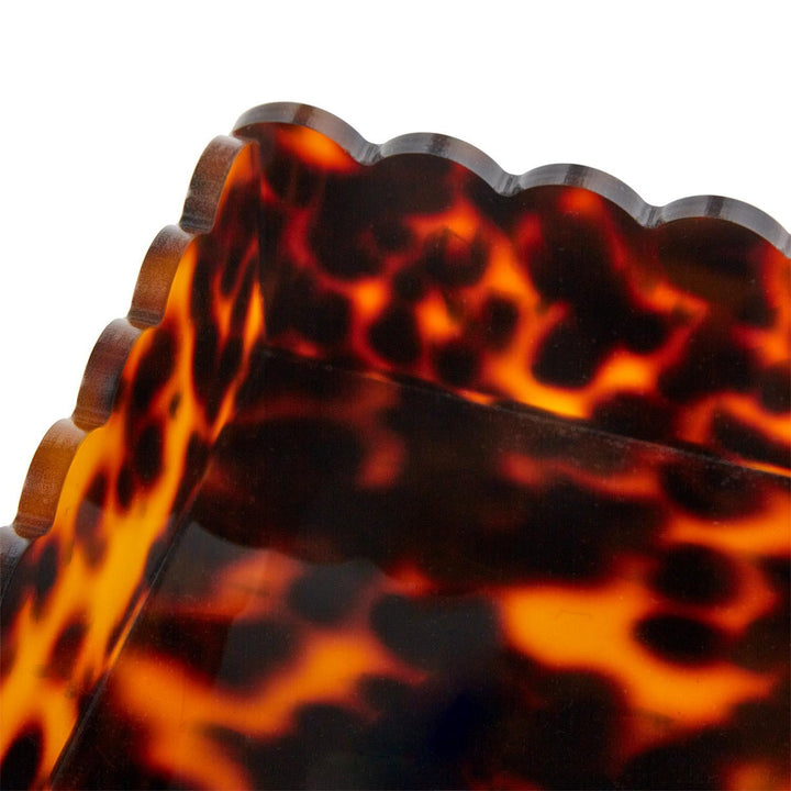 Close-up of tortoiseshell patterned sunglasses with a scalloped edge.