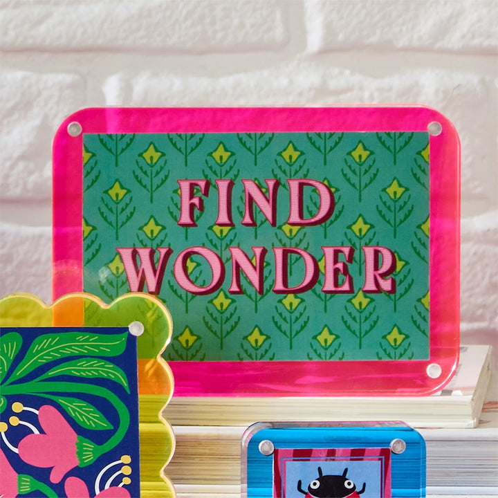 Colorful children's book with 'Find Wonder' text on a white brick wall background