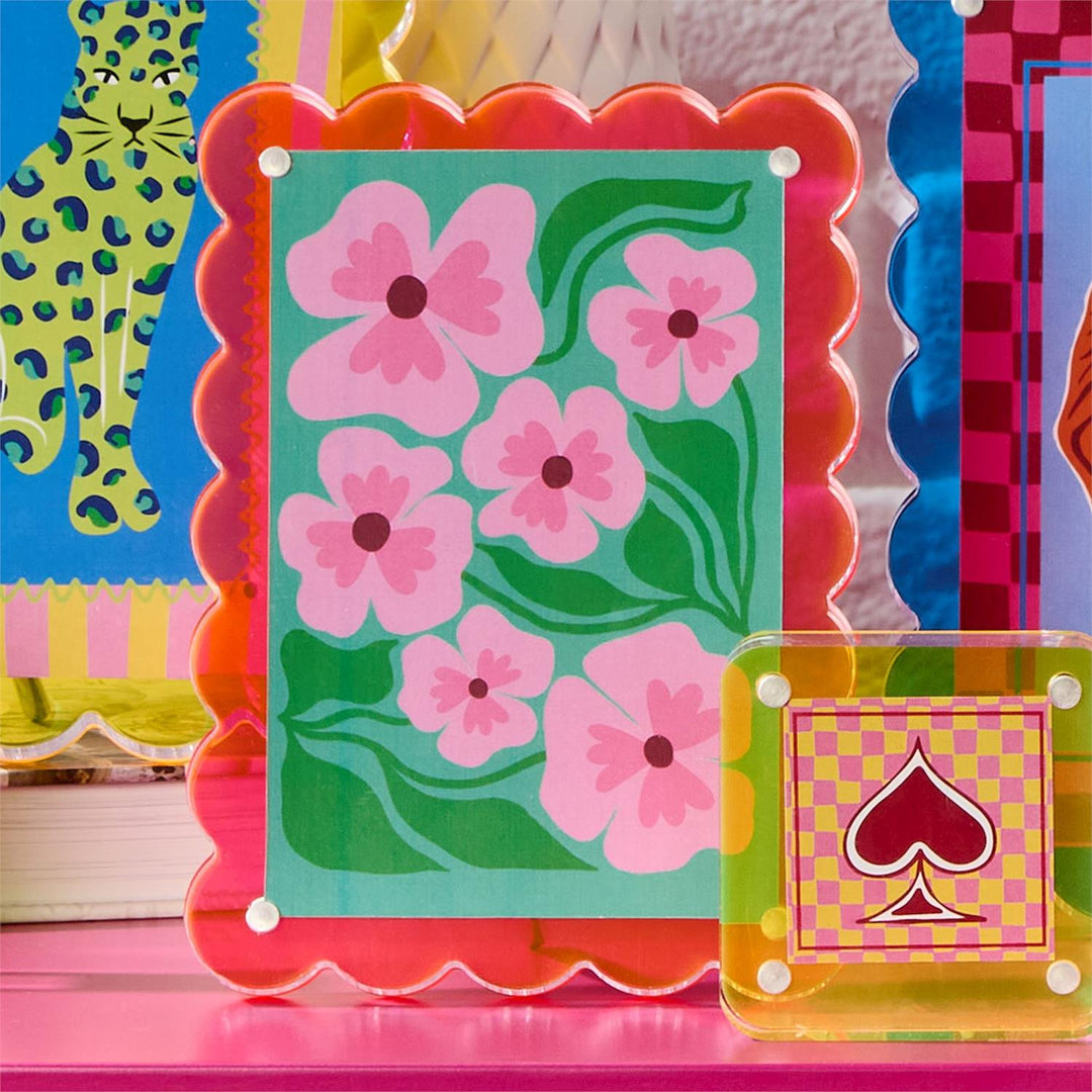 Colorful card with pink flowers and a red spade symbol on a pink surface.