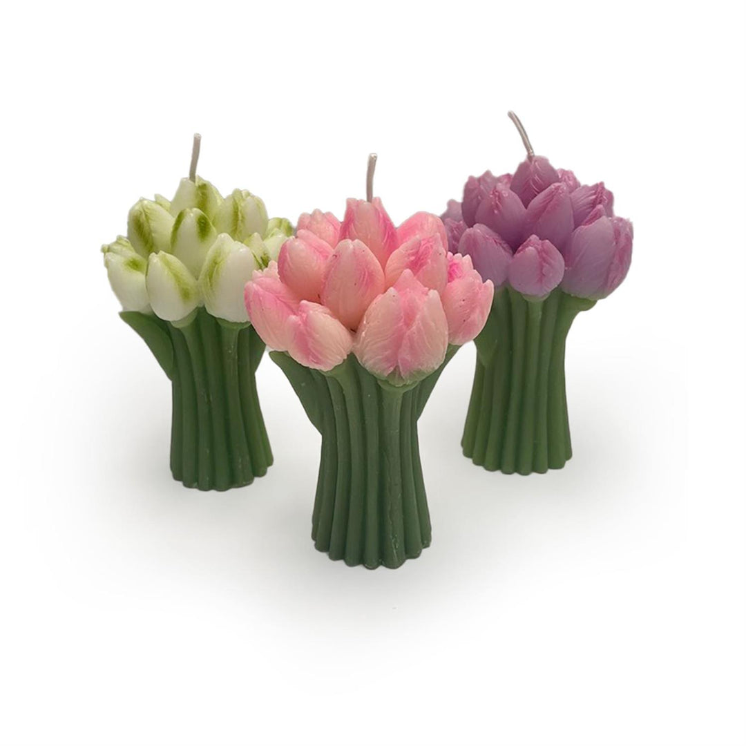 Three tulip-shaped candles in green, pink, and purple on a white background