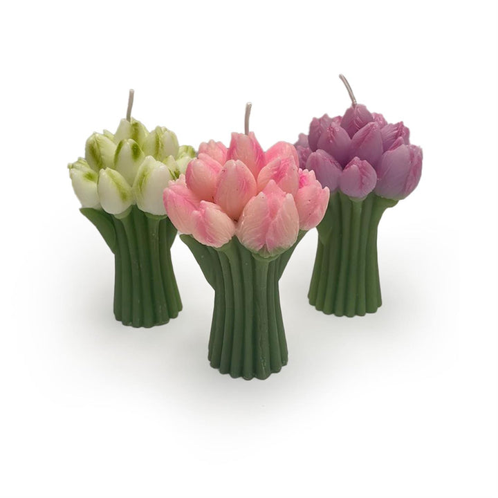 Three tulip-shaped candles in green, pink, and purple on a white background