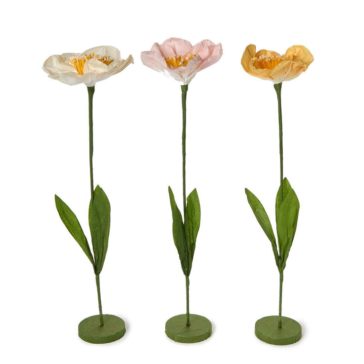 Three artificial tulip flowers on green stems with bases against a white background