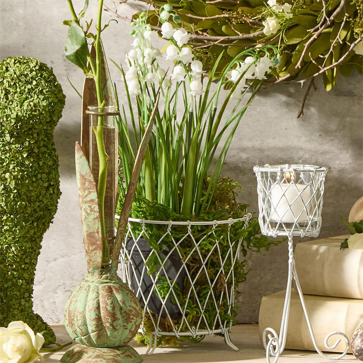 Decorative arrangement with flowers, candles, and greenery on a neutral background