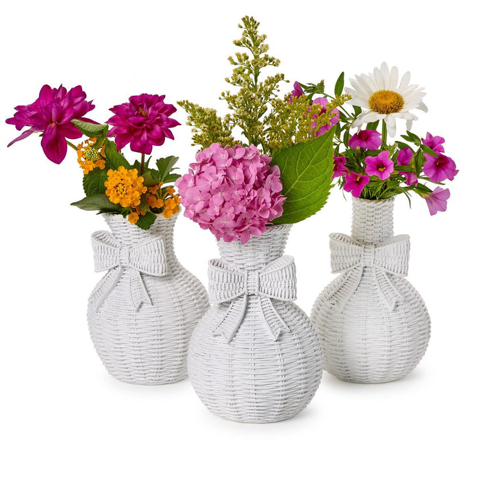 Three white woven vases with floral arrangements on a white background