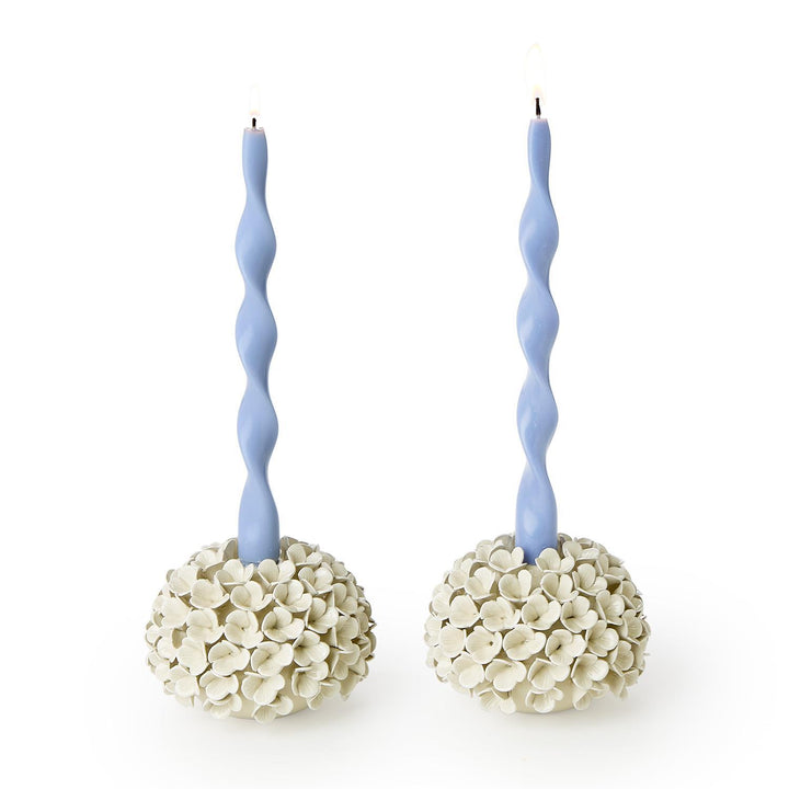Two candle holders with twisted blue candles on a white background