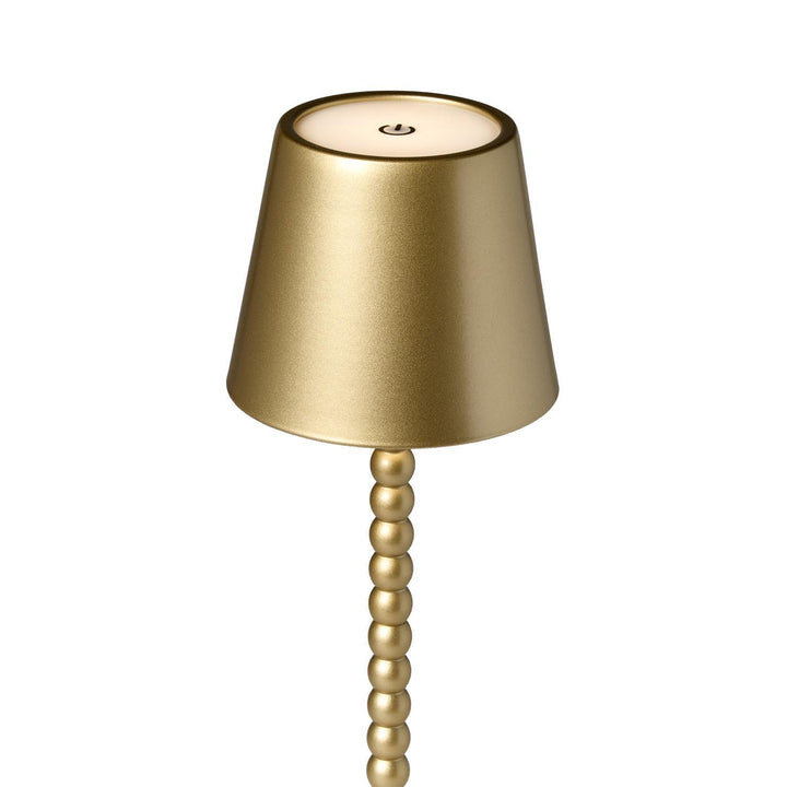 Gold table lamp with a beaded base on a white background