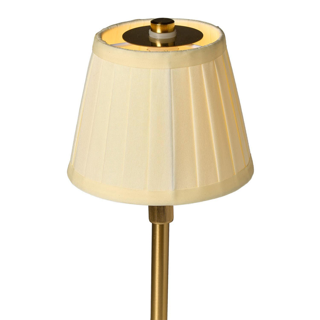 Lamp with a beige pleated shade and brass base on a white background