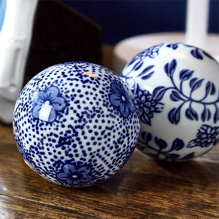 Two ceramic balls with blue floral patterns on a wooden surface
