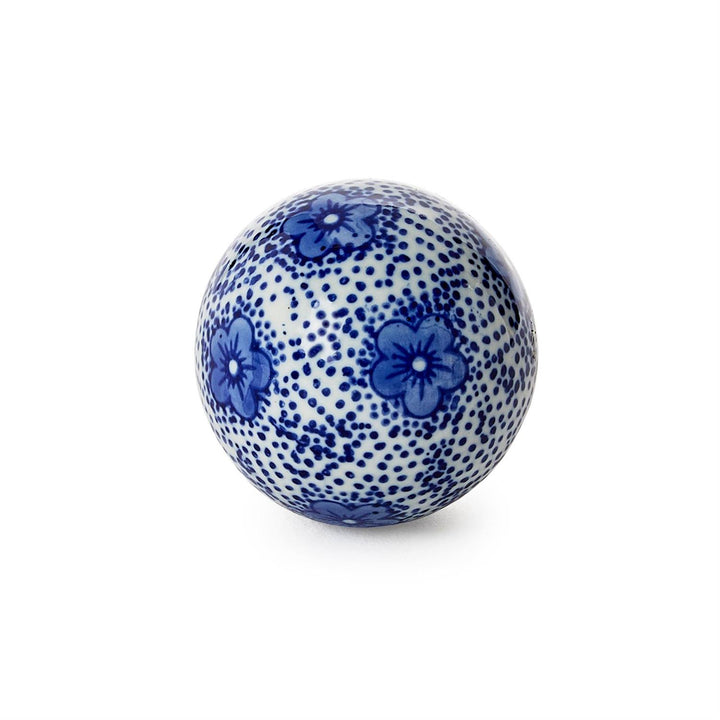 Blue and white ceramic ball with floral pattern on a white background