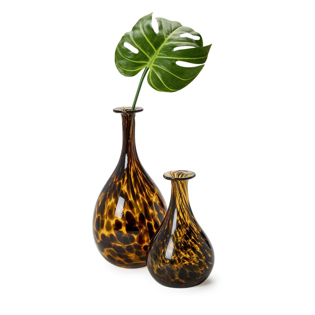 Two tortoiseshell patterned vases with a single green leaf on a white background