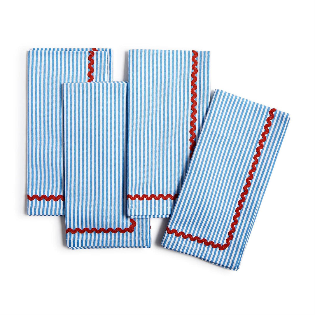 Set of four blue and white striped napkins with red trim on a white background