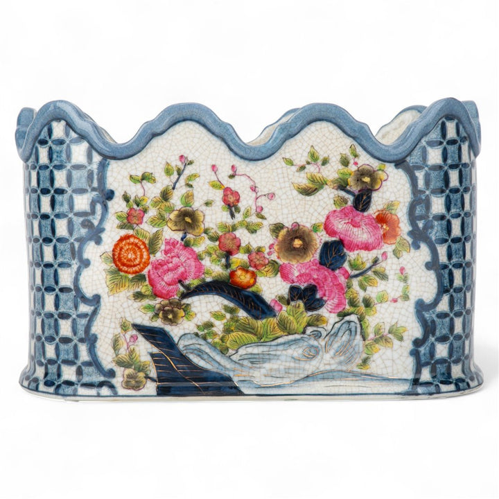 Decorative ceramic planter with floral design and blue checkered border on a white background