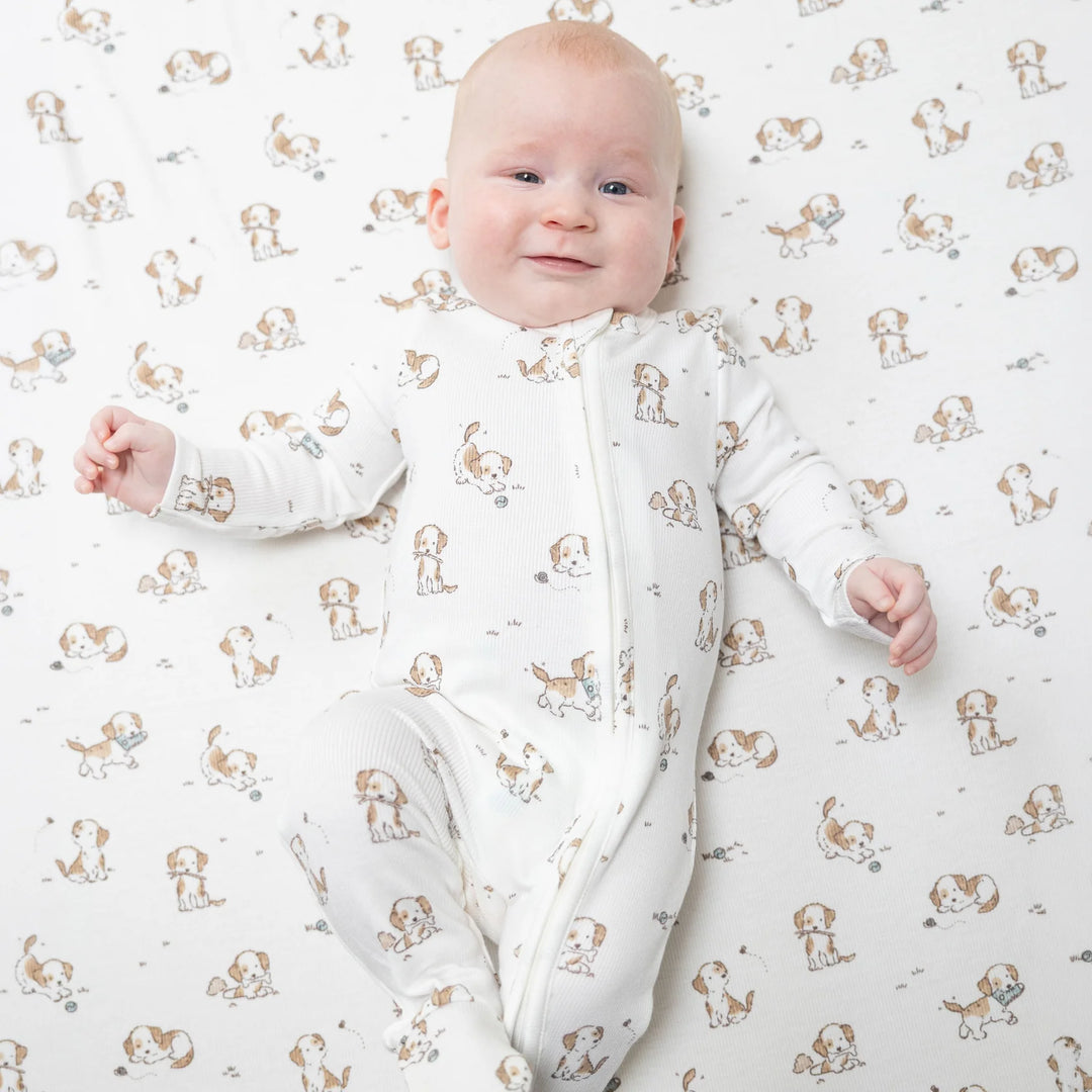 Angel Dear Explorer Puppy Blue 2-way Zipper Footie worn by a baby in a lifestyle view highlighting the explorer puppy blue 2-way design
