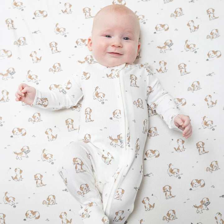 Angel Dear Explorer Puppy Blue 2-way Zipper Footie worn by a baby in a lifestyle view highlighting the explorer puppy blue 2-way design