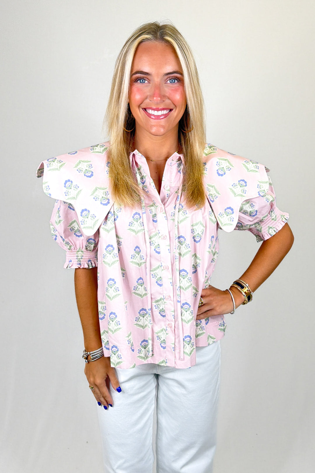 Woman wearing a floral blouse with ruffled sleeves on a plain background