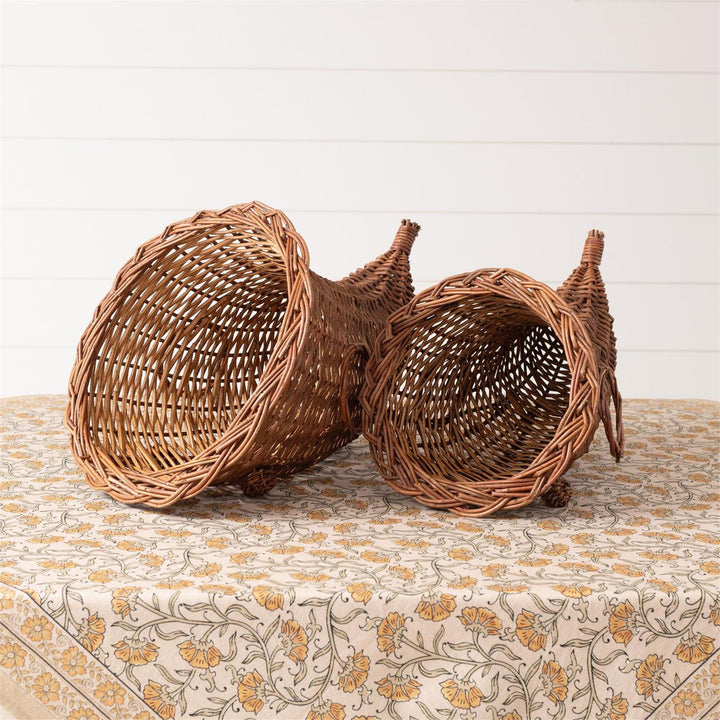 Three wicker baskets on a floral-patterned fabric with a white wooden background