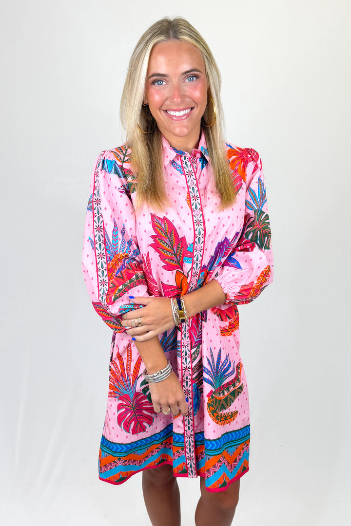 Woman wearing a colorful pink dress with floral patterns on a white background