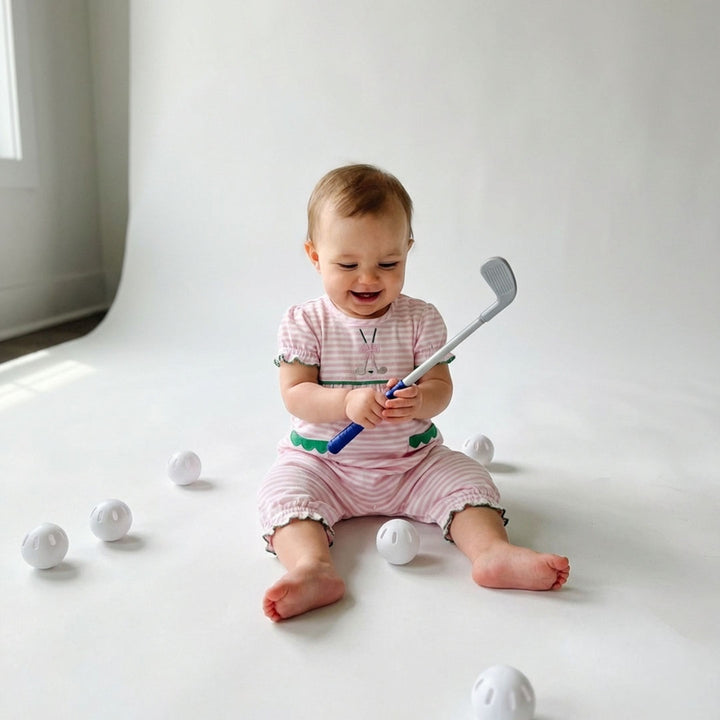 Baby playing with golf clubs and balls on a white background