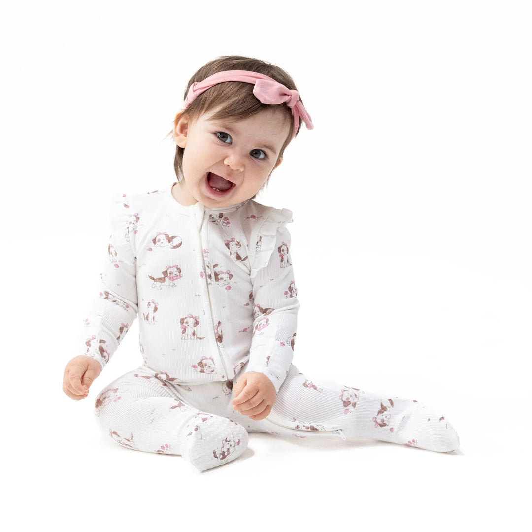 Angel Dear Explorer Puppy Pink 2-way Ruffle Sleeve Zipper Footie worn by a baby in a lifestyle view highlighting the explorer puppy pink 2-way design