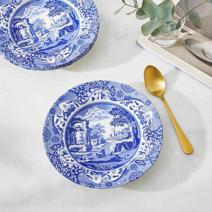 Blue and white patterned plates with a gold spoon on a light surface