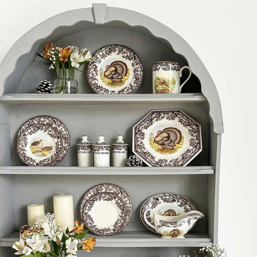 Decorative shelves with ceramic plates featuring animal designs, candles, and flowers.