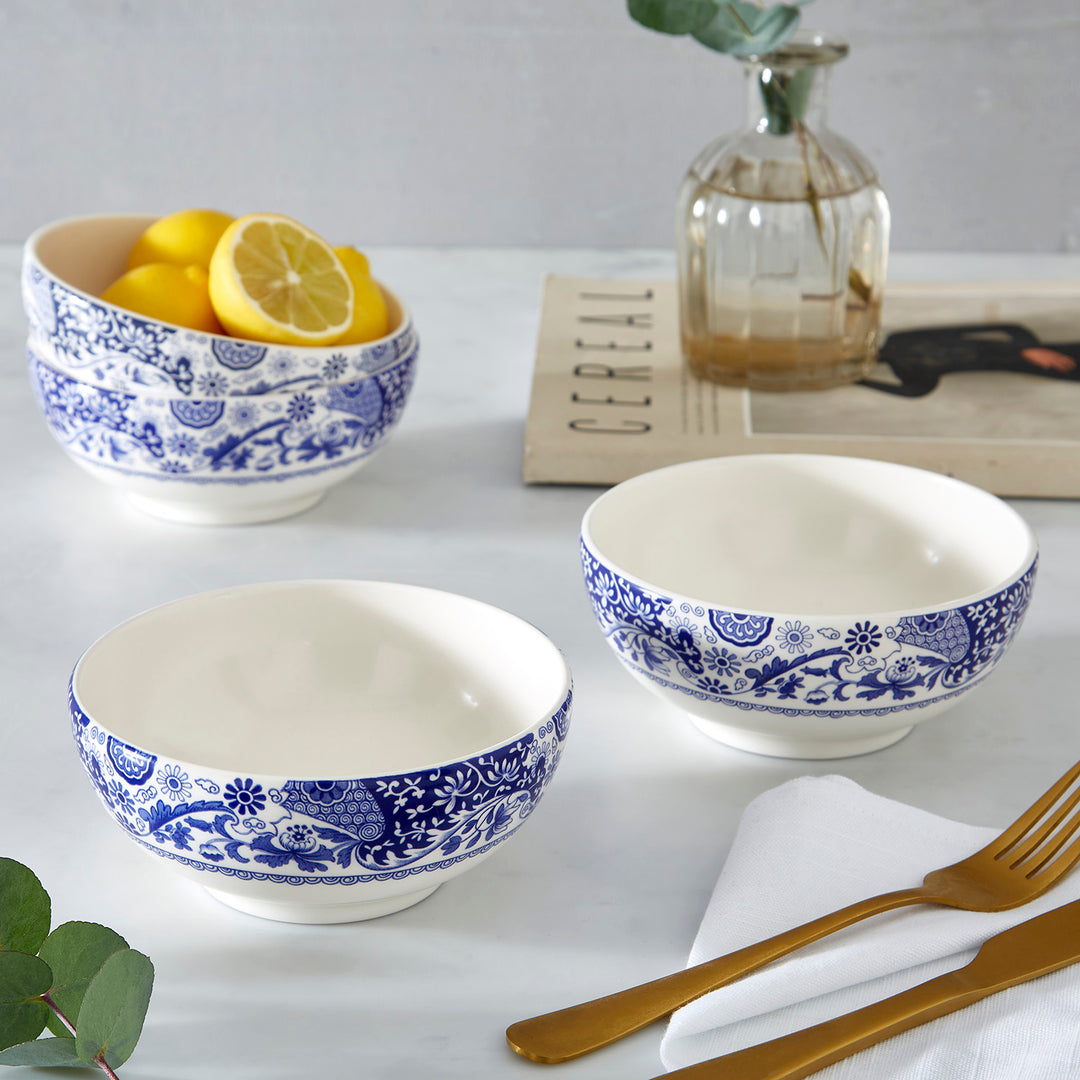 Set of three ceramic bowls with blue floral patterns on a white surface with gold cutlery.
