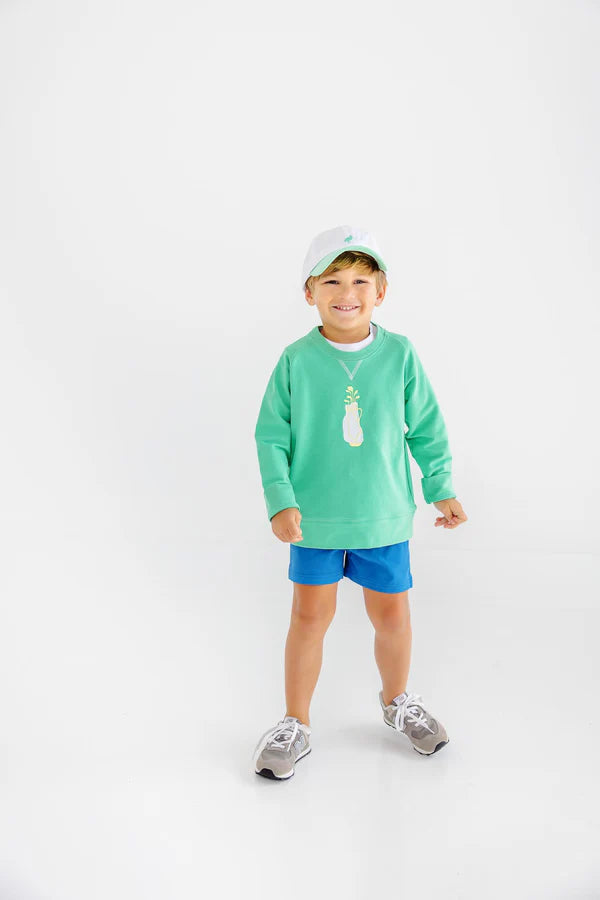 Child wearing a green shirt and blue shorts on a white background