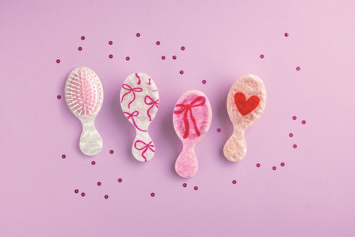 PINK AND RED HAIR BRUSHES ON PURPLE BACKGROUND