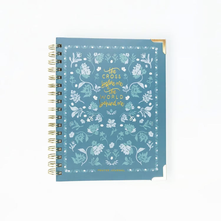 A blue spiral-bound notebook with a floral pattern and gold foil text reading &