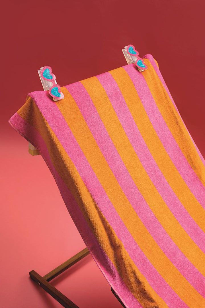 ORANGE AND PINK STRIPE TOWEL WITH SEASHELL EMBROIDERED AND YELLOW BOTTOM BORDER ON CHAIR ON RED BACKGROUND